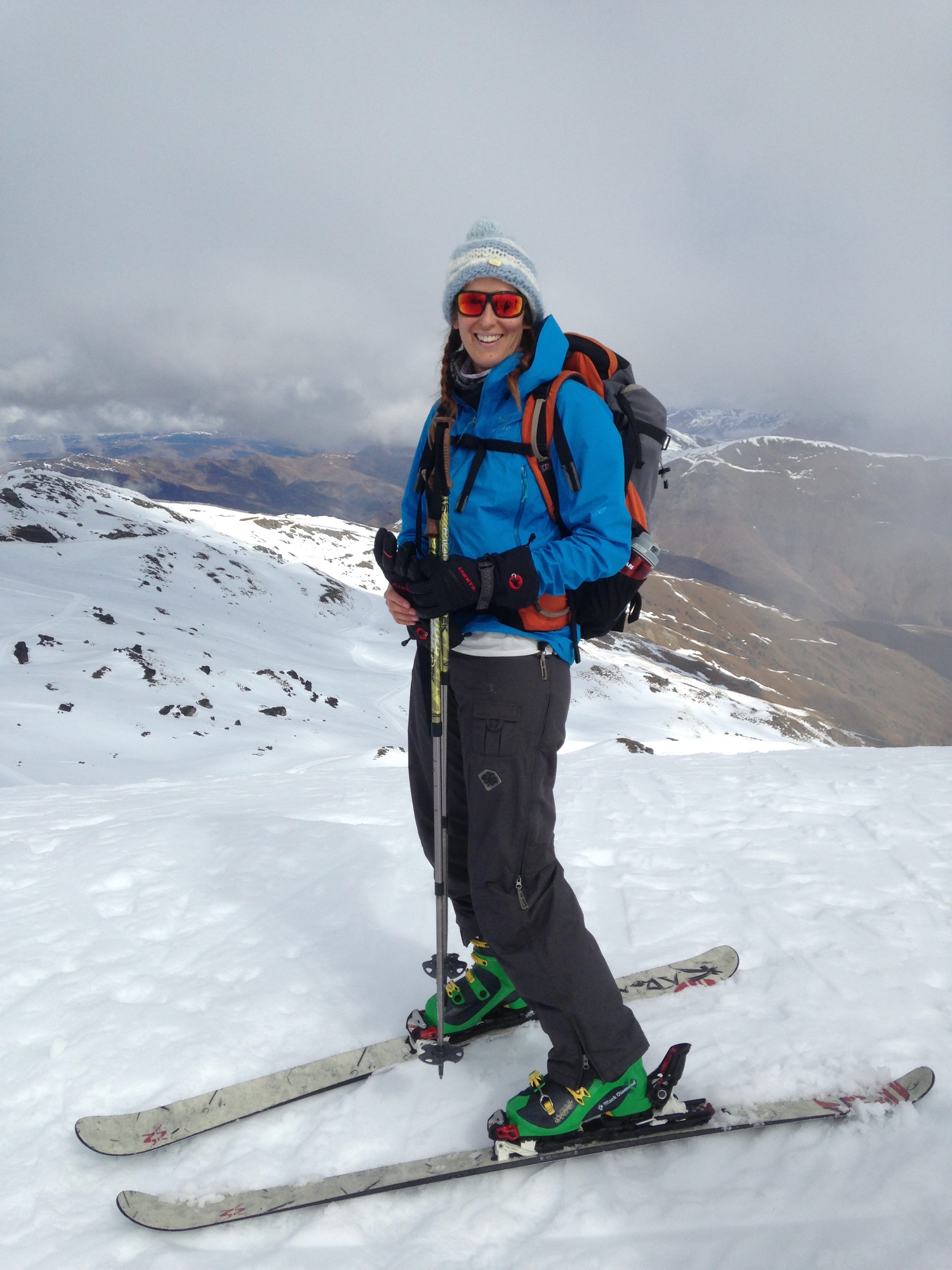 Ski tourer smiling on a snowy ridge in the mountains